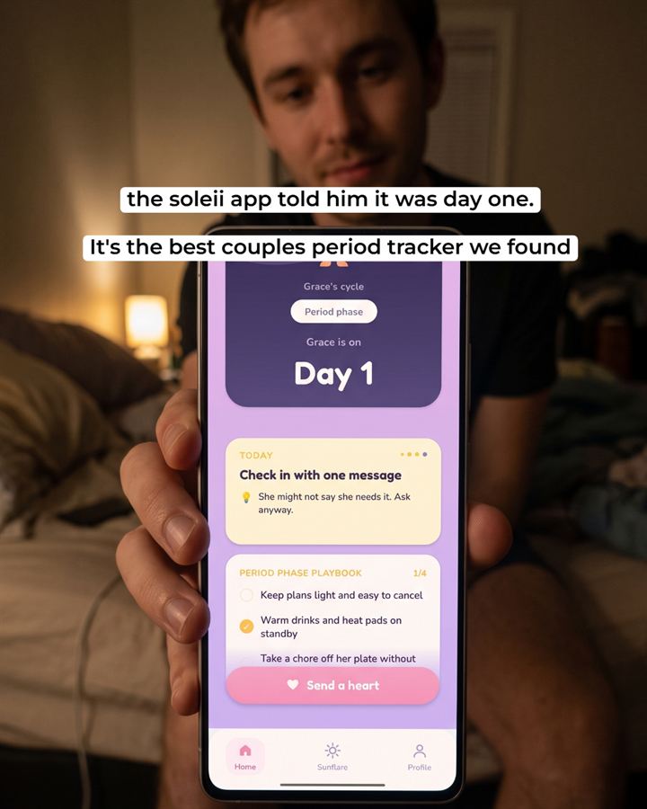 A man sitting on a bed, holding his phone up to the camera. On the screen, the Soleii app: 'Grace's cycle, Period phase, Grace is on, Day 1', a check-in card and a Send a heart button. Text over the photo: 'the soleii app told him it was day one. It's the best couples period tracker we found'.